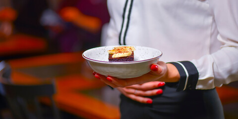 Waiter in white uniform, shirt, bringing the ordered dessert and in a cafe or restaurant. Copy space banner.