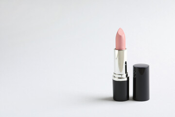 Fototapeta premium Pale pink lipstick on light background. Space for text
