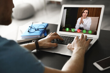 Man using laptop at table for online consultation with psychologist via video chat, focus on screen