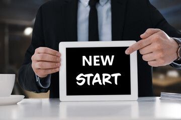 Obraz premium Fresh opportunities. Business owner holding tablet with text New Start at table, closeup