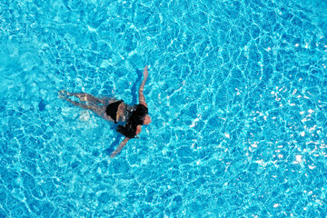Fototapeta premium Beautiful young woman swimming in pool, top view. Space for text