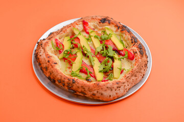 Close-up of a delicious smoked salmon pizza with cheese, avocado and smoked salmon. Sea-food. Orange background.