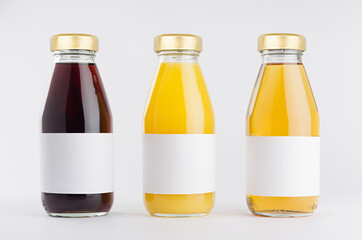 Yellow, red fruit and berries juices collection in glass bottles with cap, white blank labels in...