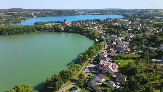 Aerial backwards shot of natural lake,road with cars and small village near Gdansk,Poland