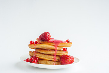 The pancakes are poured with pink strawberry jam on a white background.
