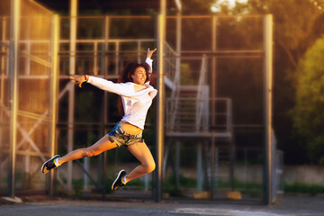 Beautiful brown-haired girl dancing on the street on a summer sunny evening