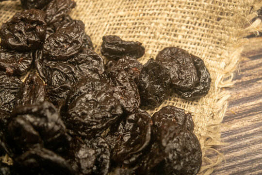 Dried prunes in bulk on burlap with a rough texture. Close up.