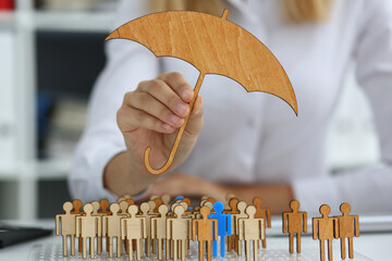 Cropped head of female holding wooden umbrella in hand and covering statuettes of human with it...