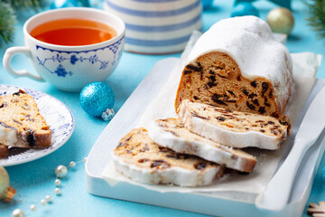 Christmas stollen. Traditional German festive dessert with cup of tea. Blue background. Close up.