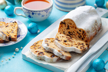Christmas stollen. Traditional German festive dessert with cup of tea. Blue background. Close up.