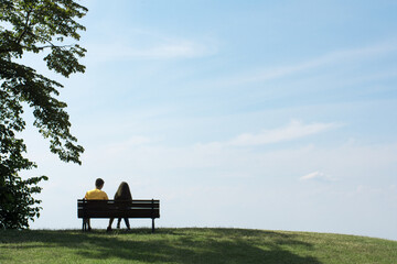 Beautiful blue sky and a couple sitting on bench. 