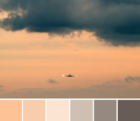 Beautiful dramatic gray and bright orange clouds in the sky, a small silhouette of airplane. Color palette swatches, natural combination of colors.