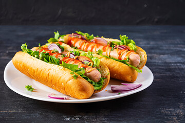 Homemade hot dog with sausage, salad, carrot, cucumber and tomato on wooden background