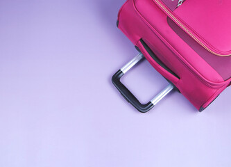 Travel concept.Top view of pink suitcase on purple background