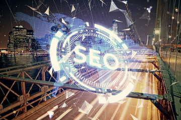 SEO hologram on city view with skyscrapers background double exposure. Search optimization concept.