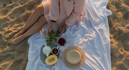 a girl with vitiligo sits on a white sheet on the beach and meets the dawn, breakfast on the beach,...