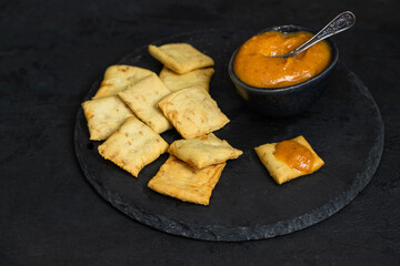 Almogrote, famous La Gomera cheese paste, in black ceramic bowl  with crusty crackers on background. Its popular appetizer served in many restaurants in Canary Islands