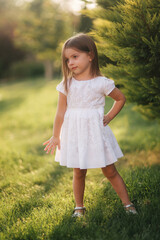 Beautiful little girl in white dress walking outdoors on back yaer of home. Happy kid