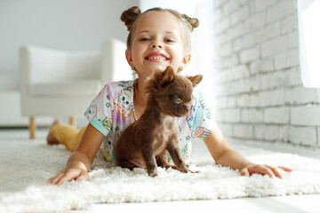Child with a dog. Little girls play with a dog on the carpet at home. High quality photo.