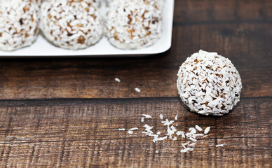 Homemade energy balls with dried apricots, raisins, dates, prunes, walnuts and coconut. Healthy sweet food. Energy balls in a plate on a wooden background. Close up. Side view. Copy space