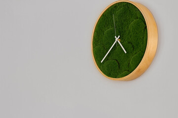 Photo of a clock on the wall, a round wooden clock with green grass on the dial.