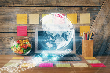 Double exposure of desktop with computer and world map hologram. International data network concept.