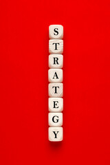 The word strategy written on wooden cubes on red background. developing or building a strategy concept.