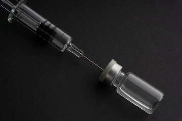 Closeup syringe and vials on black background. Healthcare dan Copy Space concept