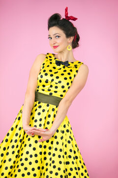 Retro girl. Beautiful woman in a dress with polka dots on a bright background.