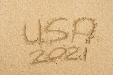Hand written sign on a yellow warm sand  USA and 2021
