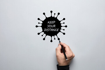 Male hand drawing a coronavirus with keep your distance text. Concept of social distancing and protection against covid 19.