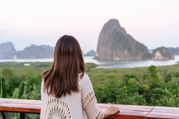 Fototapeta na wymiar Young Asian traveller woman sit and see the mountain in early morning at the Sametnangshe Island viewpoint, Phang-Nga, Thailand.