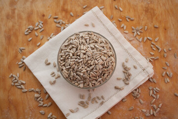 Sunflower seeds in a bowl on a white serviette. Wooden background
