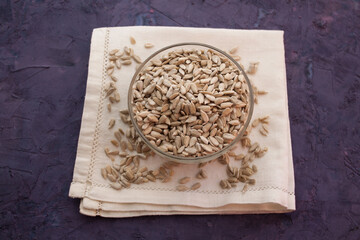 Sunflower seeds in a bowl on a white serviette. Violet grunge background

