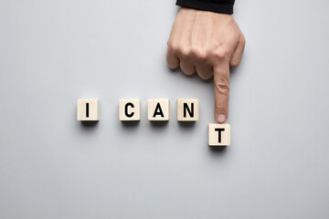 Hand moving letter and transforming the word I can't into I can on wooden cubes. Positive thinking, motivation and confidence concept.