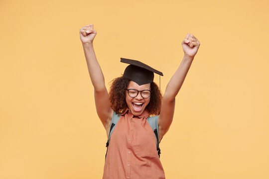 Hilarious Emotional Afro-American Student Girl In Academic Cap Keeping Eyes Closed While Celebrating Her Success