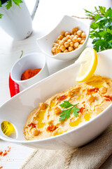 hummus paste with lemon and chilli on white background