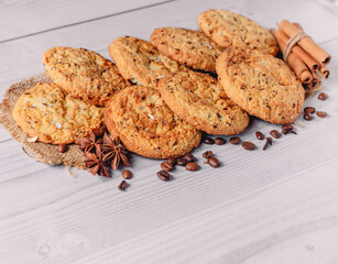 Fresh baked oatmeal cookies decorated with coffee beans,anise, cinnamon sticks, cloves on  white wooden table background with copy space. Image design for menu layout. Tasty and junk food concept.