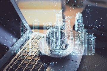 Desktop computer background in office and big town buildings hologram drawing. Double exposure. Smart city concept.