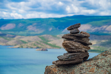 Zen concept. A stone object on the top of a mountain against the backdrop of Lake Baikal. Stone pyramid for meditation. Harmony and Meditation. Zen stones.