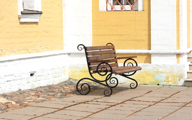 Fototapeta na wymiar Street bench near the church wall in the courtyard.