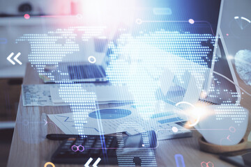 Double exposure of desktop with computer and world map hologram. International data network concept.