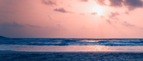 Dawn on the ocean. Sea with waves, sandy beach. Image with retro toning. Beautiful landscape. Banner panorama format