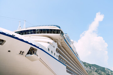 Close-up of a large white moored cruise liner on a jetty near the old town of Kotor in Montenegro.
