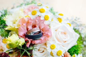 Special wedding rings with wooden look on pink flowers as a sign of commitment love and togetherness