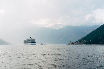Fototapeta na wymiar The cruise liner sails near the city of Perast and the islands in Montenegro.