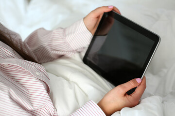 Top view cropped head of woman in pyjamas relaxing with digital tablet just after waking up