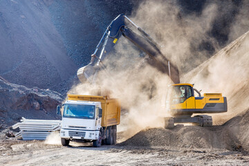 The excavators are digging and loading to a truck in the construction site.