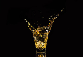 A glass of whiskey with splashes from the ice cube over black background. alcohol splashes. whisky...