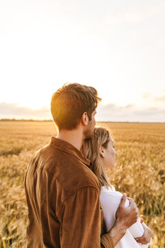 Image of young couple hugging together in golden field on countryside